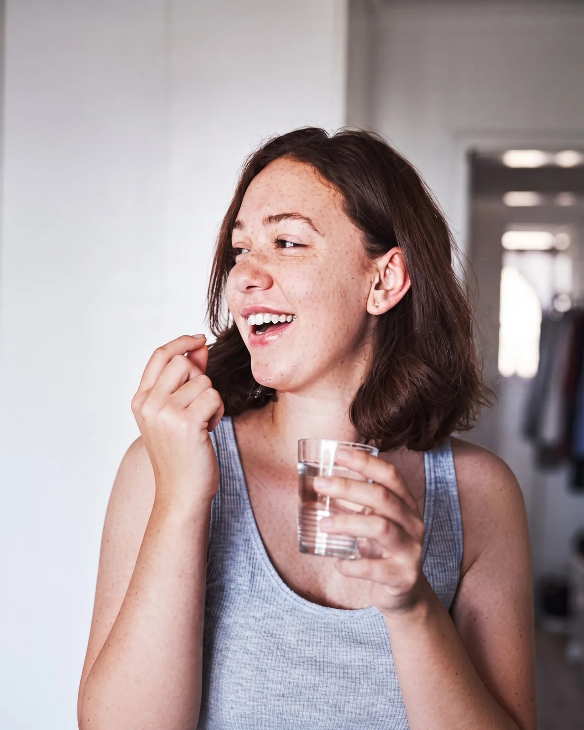 A woman taking her daily capsule with a glass of water