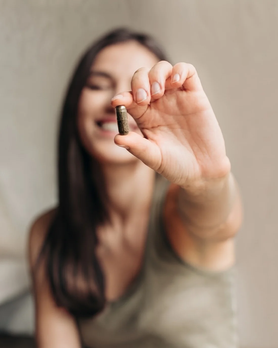 A woman holding up a single beef liver capsule