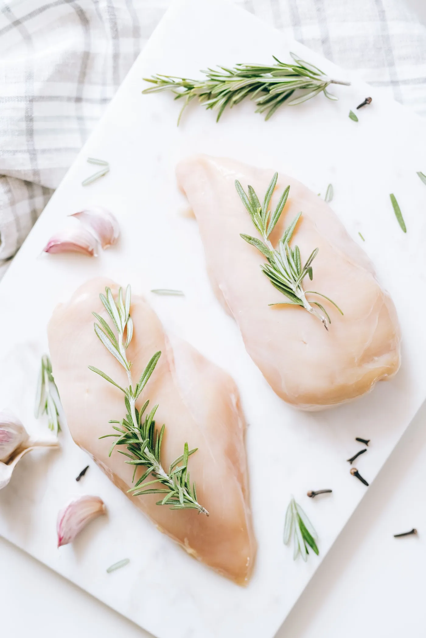 Two boneless, skinless chicken breasts on a white board