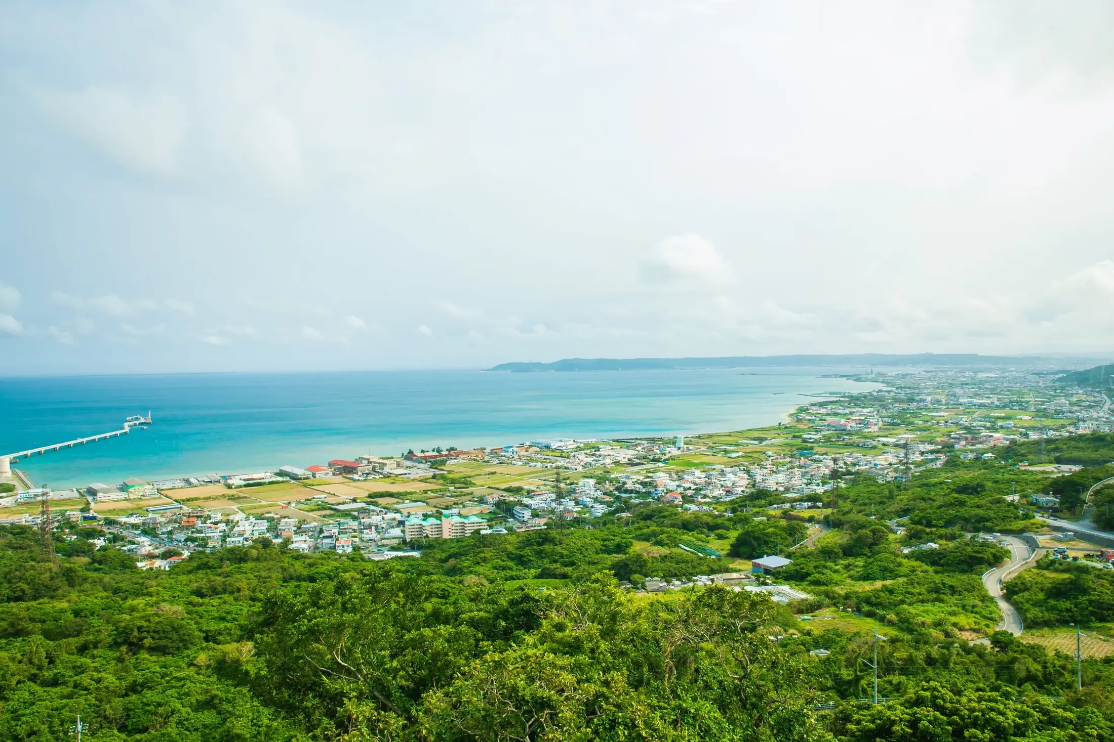 Green hills running down to a turquoise bay on the coast of Okinawa