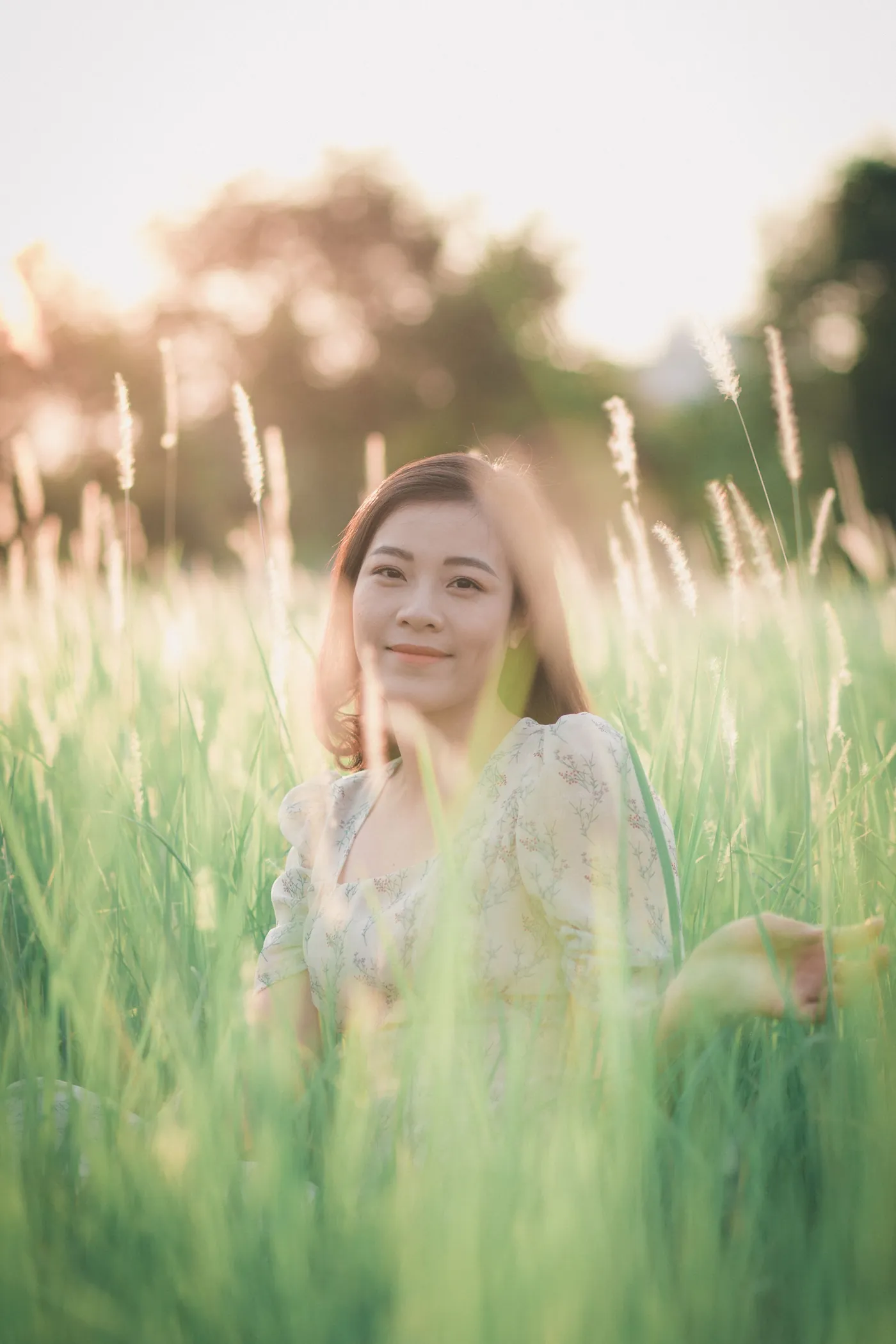 A woman smiling in a sunlit field of tall grass