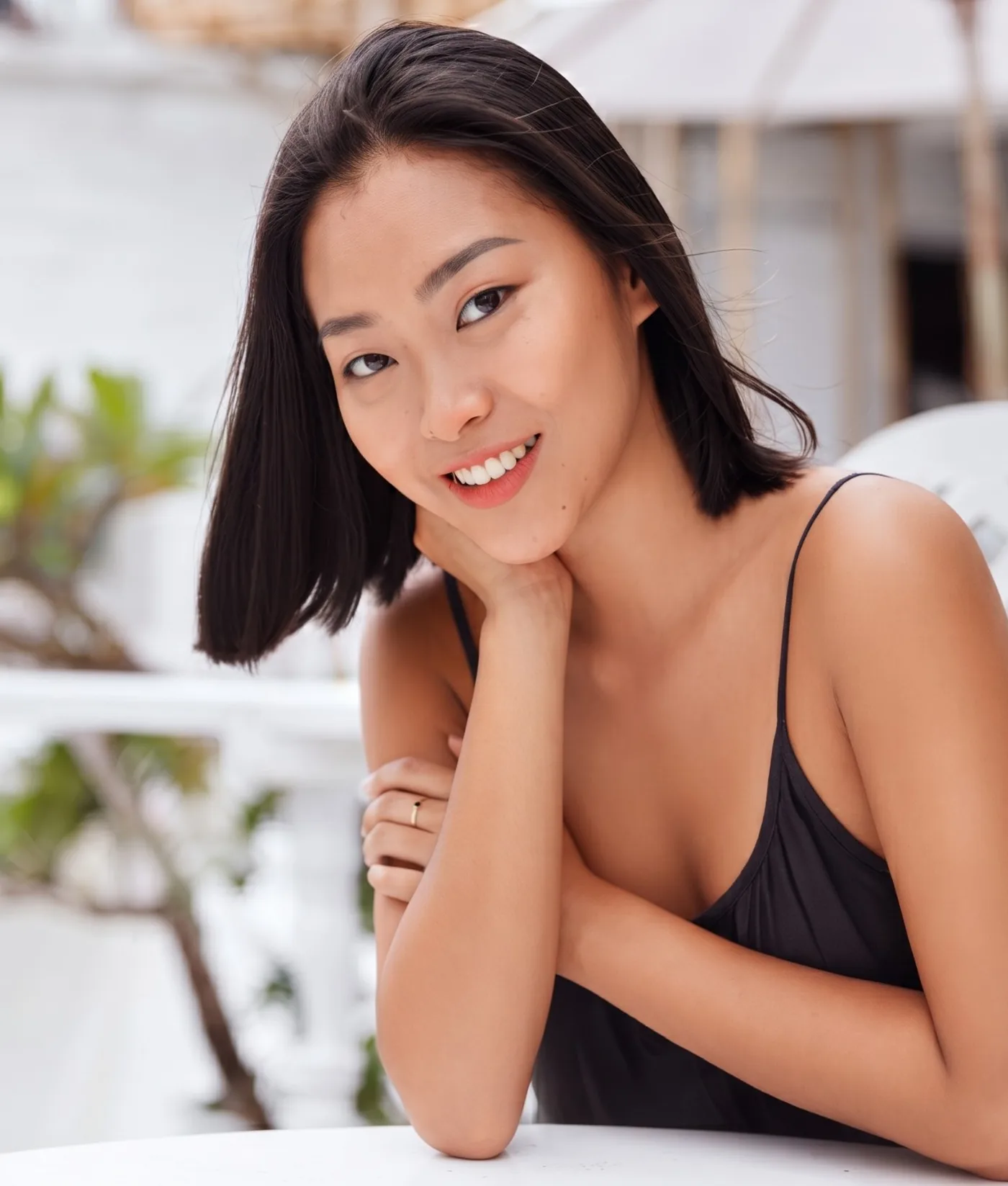 A young woman smiling at a table outdoors